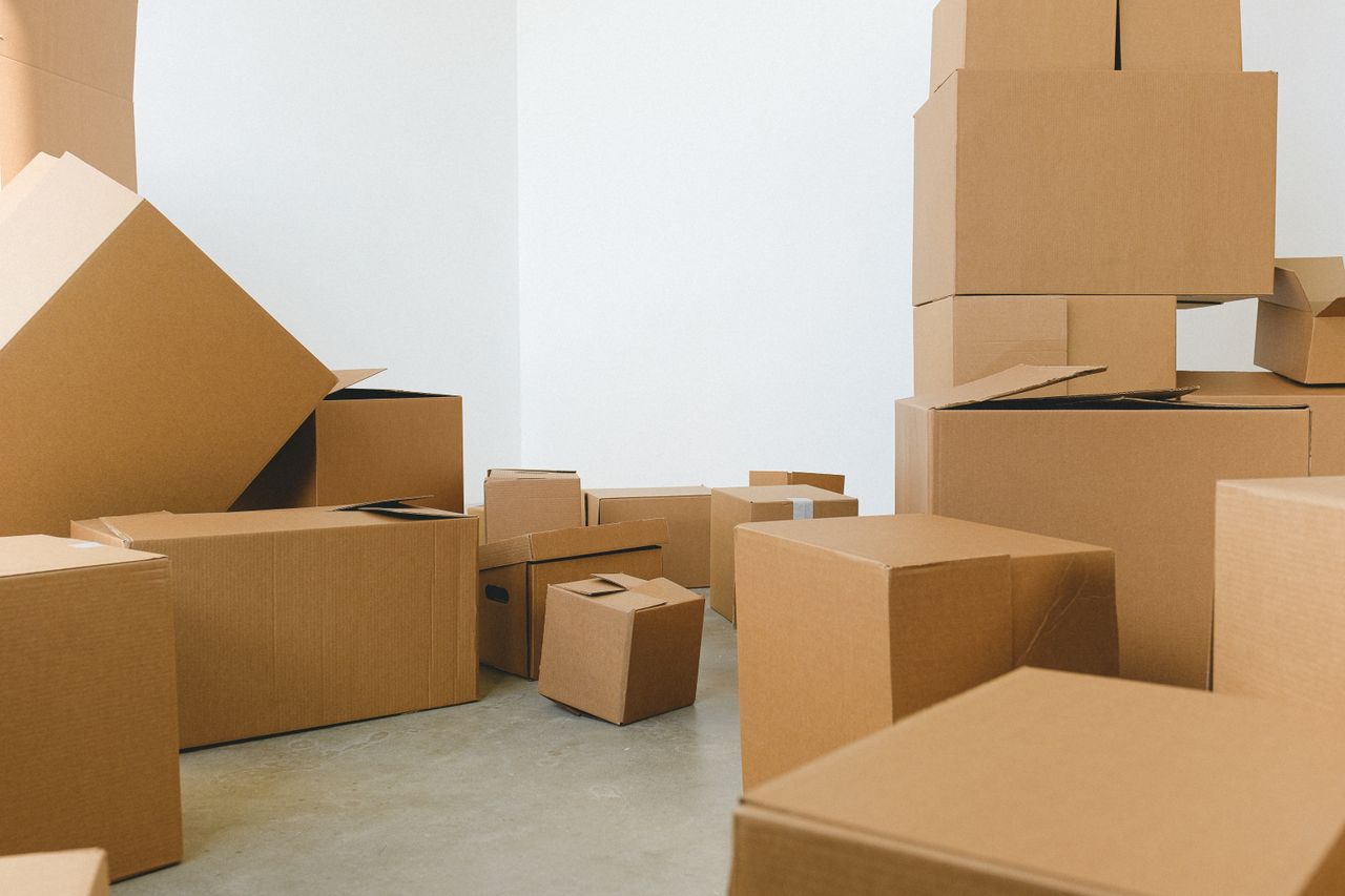 brand-01 Stack of carton boxes of various shapes and sizes scattered in floor near white walls during relocation